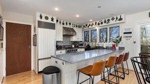 A modern kitchen with a central island, white cabinetry, and a stainless steel range hood. - Wintergreen Retreat Jacuzzi Sauna dog Friendly (Nellysford)