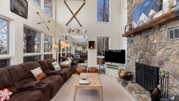 A spacious living room with a stone fireplace, a large TV, and a cozy brown leather sofa. - Wintergreen Retreat Jacuzzi Sauna dog Friendly (Nellysford)