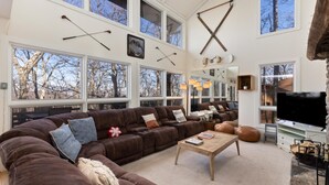 A spacious living room with a large brown leather sectional sofa, a wooden coffee table, and a stone fireplace. - Wintergreen Retreat Jacuzzi Sauna dog Friendly (Nellysford)