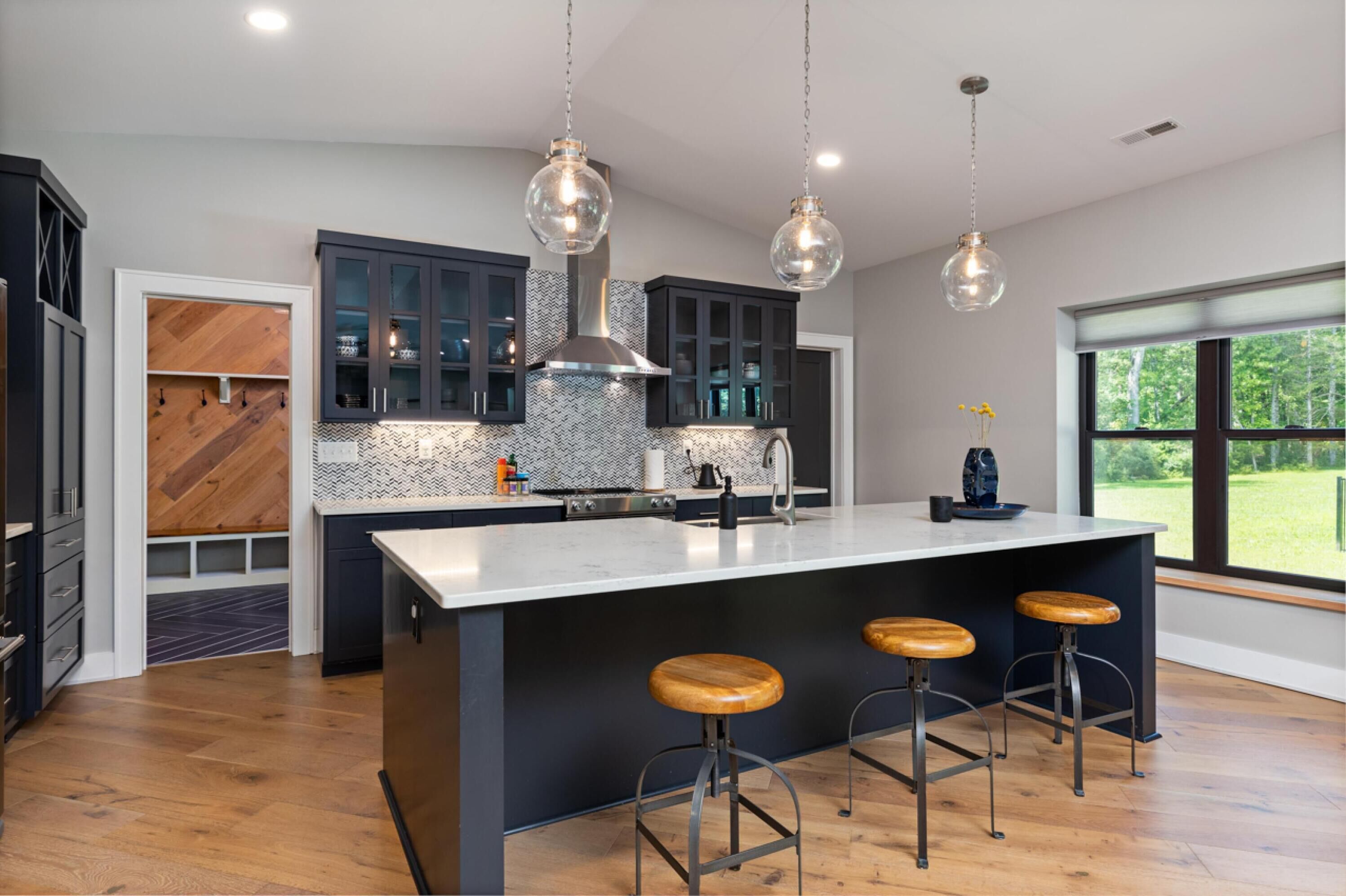 Una cocina moderna con una isla grande, taburetes de bar e iluminación colgante.