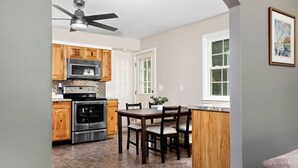 A kitchen with wooden cabinets, a microwave, an oven, and a dining table with chairs. - Waynesboro Home Near Wintergreen Charlottesville (Waynesboro)