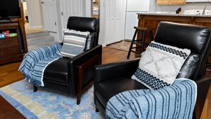A living room with two black leather chairs, a TV, and a kitchen area with wooden cabinets and a microwave. - Condo at Wintergreen Walk to Slope Pool Access (Nellysford)
