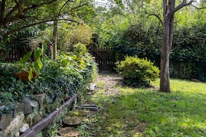 Un giardino con un muro in pietra, una recinzione in legno e un cancello di legno.