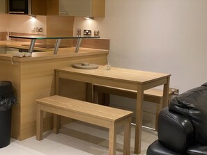 A compact kitchen with a wooden countertop, a bench, and a small table.