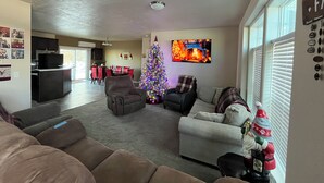 Un salon avec une cheminée, un sapin de Noël et un téléviseur fixé au mur.