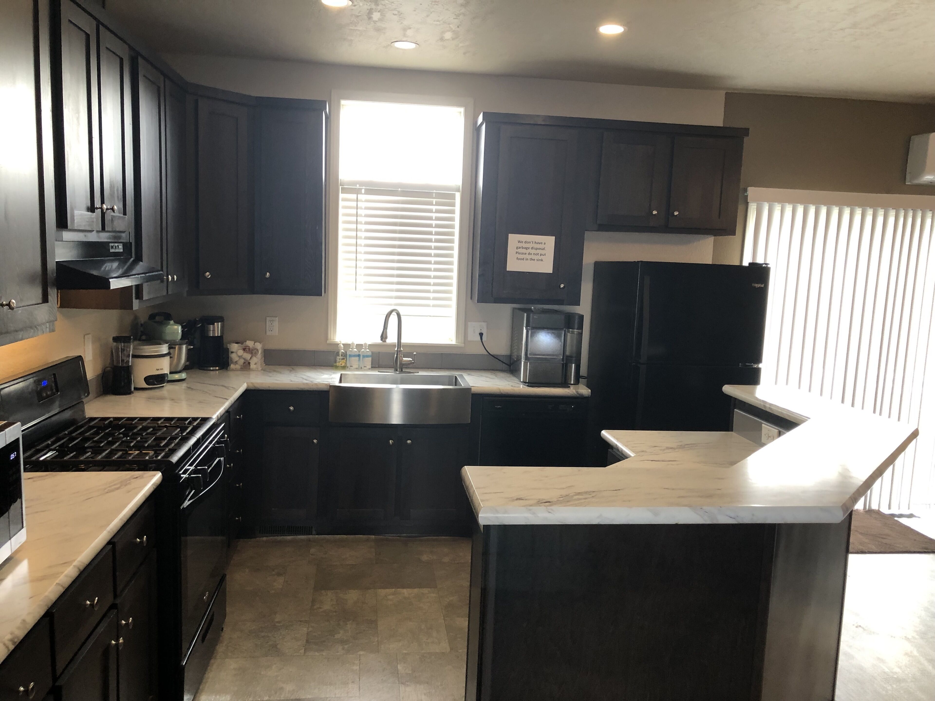 A modern kitchen with dark cabinetry, a stainless steel sink, a built-in oven, and a microwave.