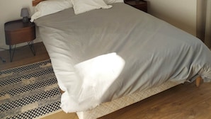 A neatly made bed with a wooden headboard, a bedside lamp, and a patterned rug on a wooden floor. - Jolie Maison Entre Mer et Montagne (Brando)