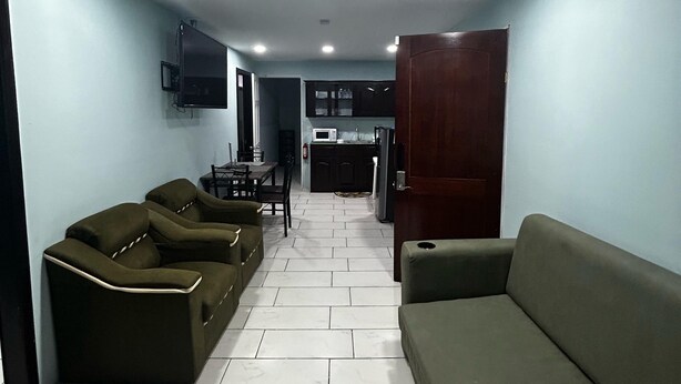 Una sala de estar con sofá, una mesa de comedor y una cocina al fondo.