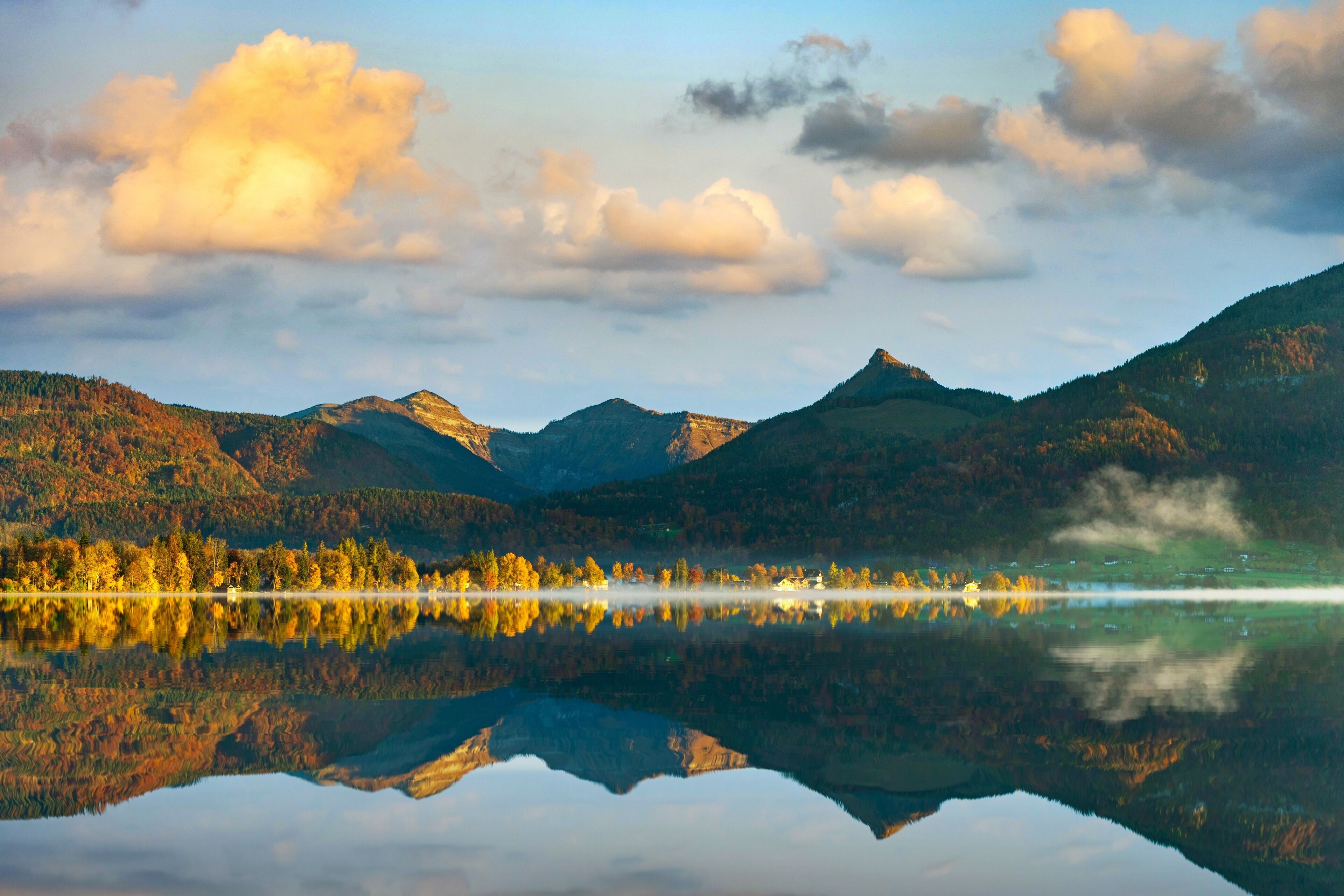 Un lago sereno que refleja montañas y árboles.