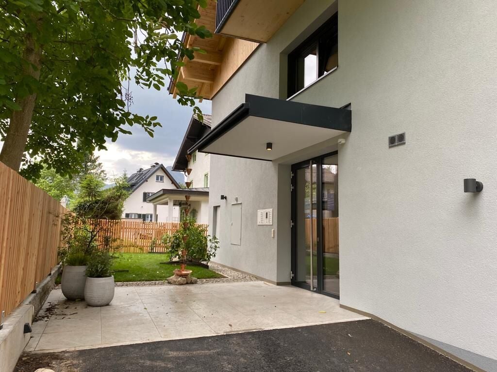 A modern house with a covered patio, a wooden fence, and a well-maintained lawn.