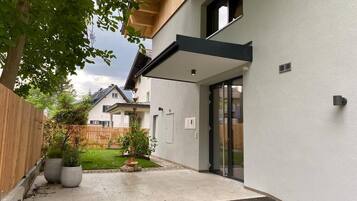 A modern house with a covered patio, a wooden fence, and a well-maintained lawn.