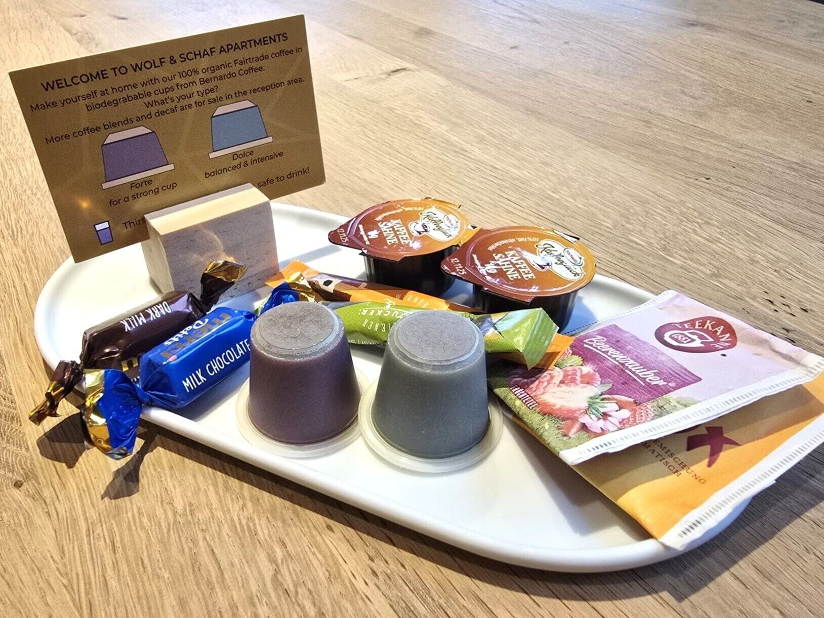 A welcome sign, a tray with coffee cups, chocolate bars, and a brochure.