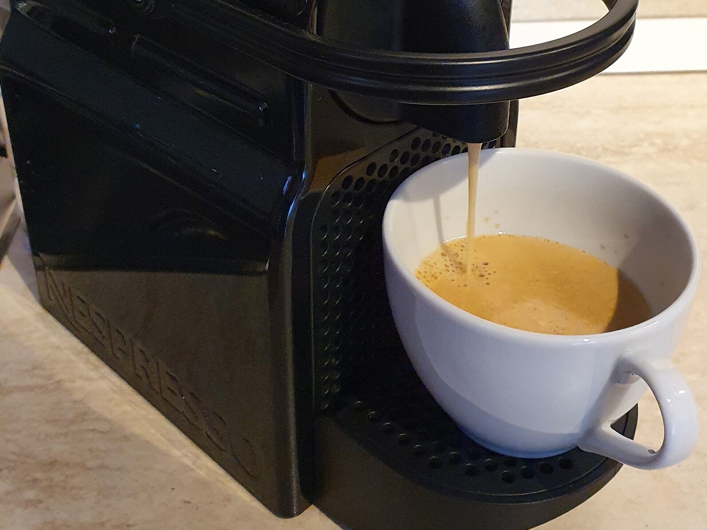A coffee maker dispensing coffee into a white cup.