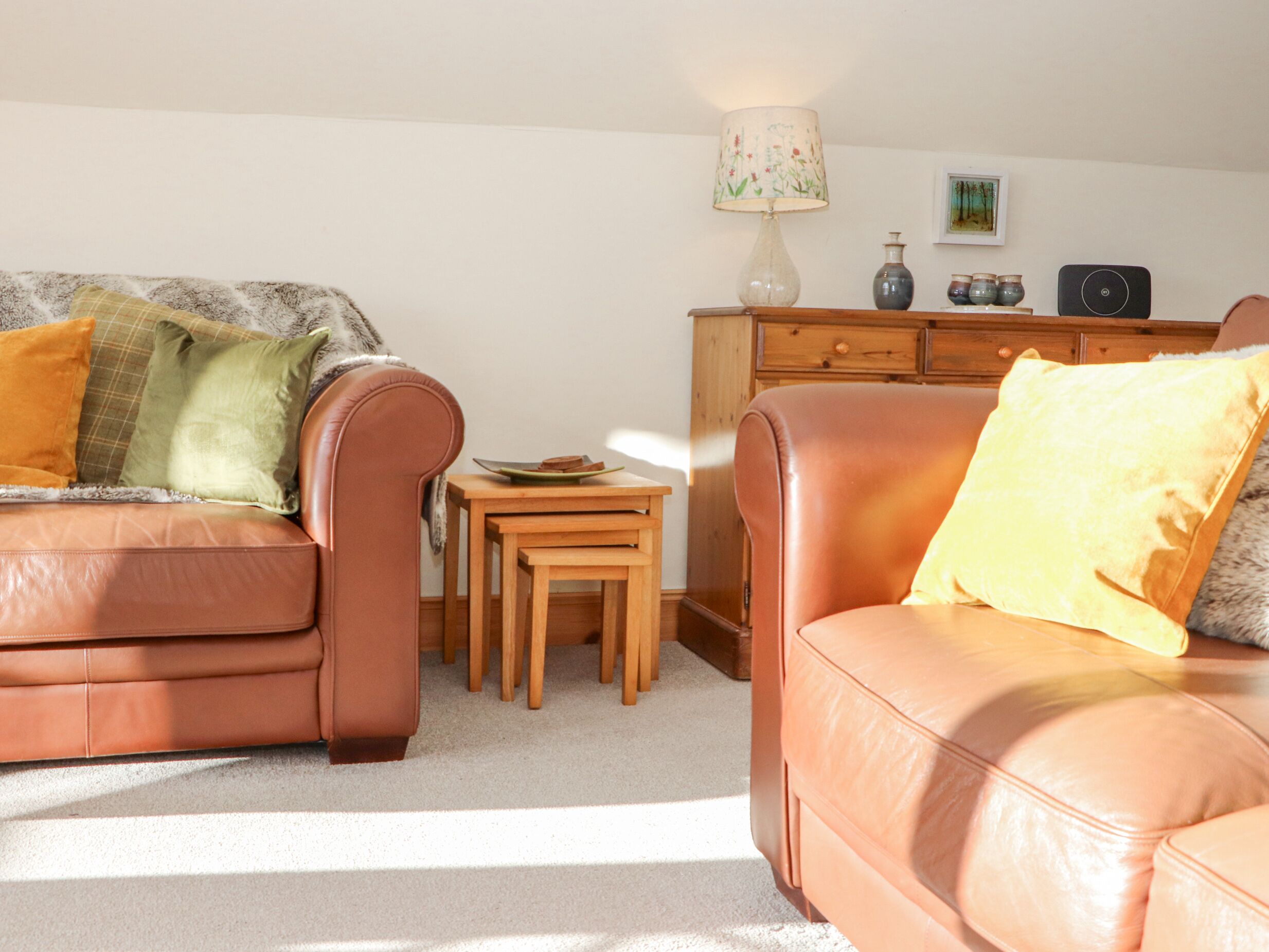 A living room with a brown leather sofa, a small wooden table, and a lamp.