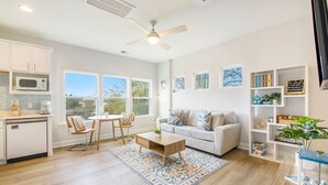 Una sala moderna con comedor, cocina y ventanas grandes.