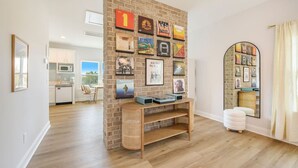 Una sala moderna con una pared de ladrillo decorativa, un mueble de madera para el entretenimiento y un espejo grande.