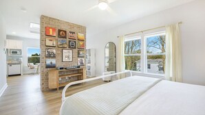 Un dormitorio con una cama grande, una pared de acento de ladrillo, una zona de comedor y una cocina.