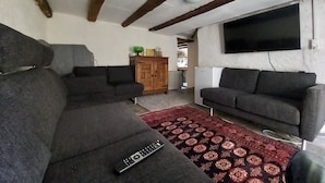 A living room with two sofas, a red patterned rug, a wooden cabinet, and a TV mounted on the wall. - Room-"casa Coerente" Cavergno - Room #4 (Cevio)
