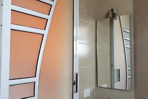 Contemporary bathroom with a large mirror and unique door design.