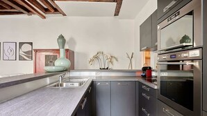 A modern kitchen with grey cabinetry, stainless steel appliances, and a wooden ceiling.