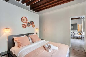 Une chambre d’hôtel avec un lit, des lampes de chevet, un mur décoré d’assiettes et une vue sur la cuisine.