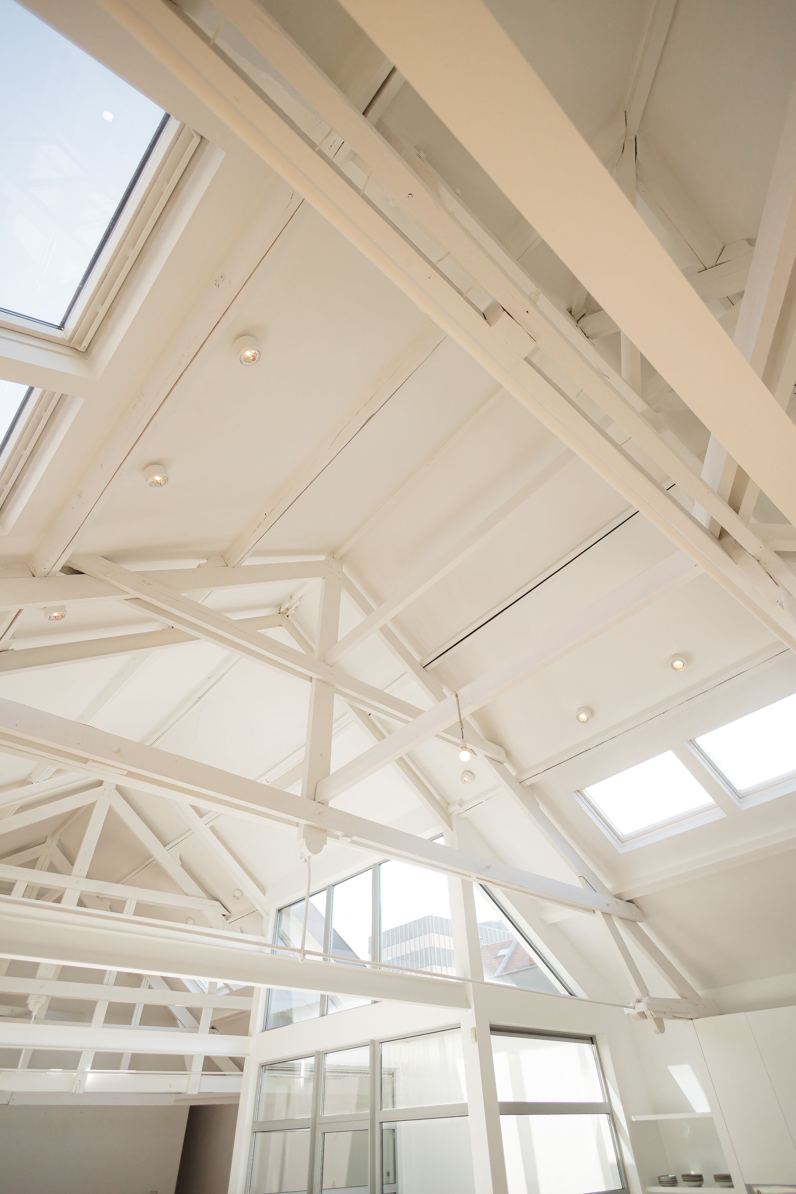 Un soffitto alto con lucernari e travi a vista, che suggerisce un ambiente interno ampio e luminoso.