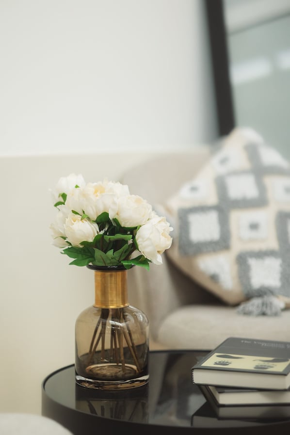 A clear glass vase with white flowers on a round black table.