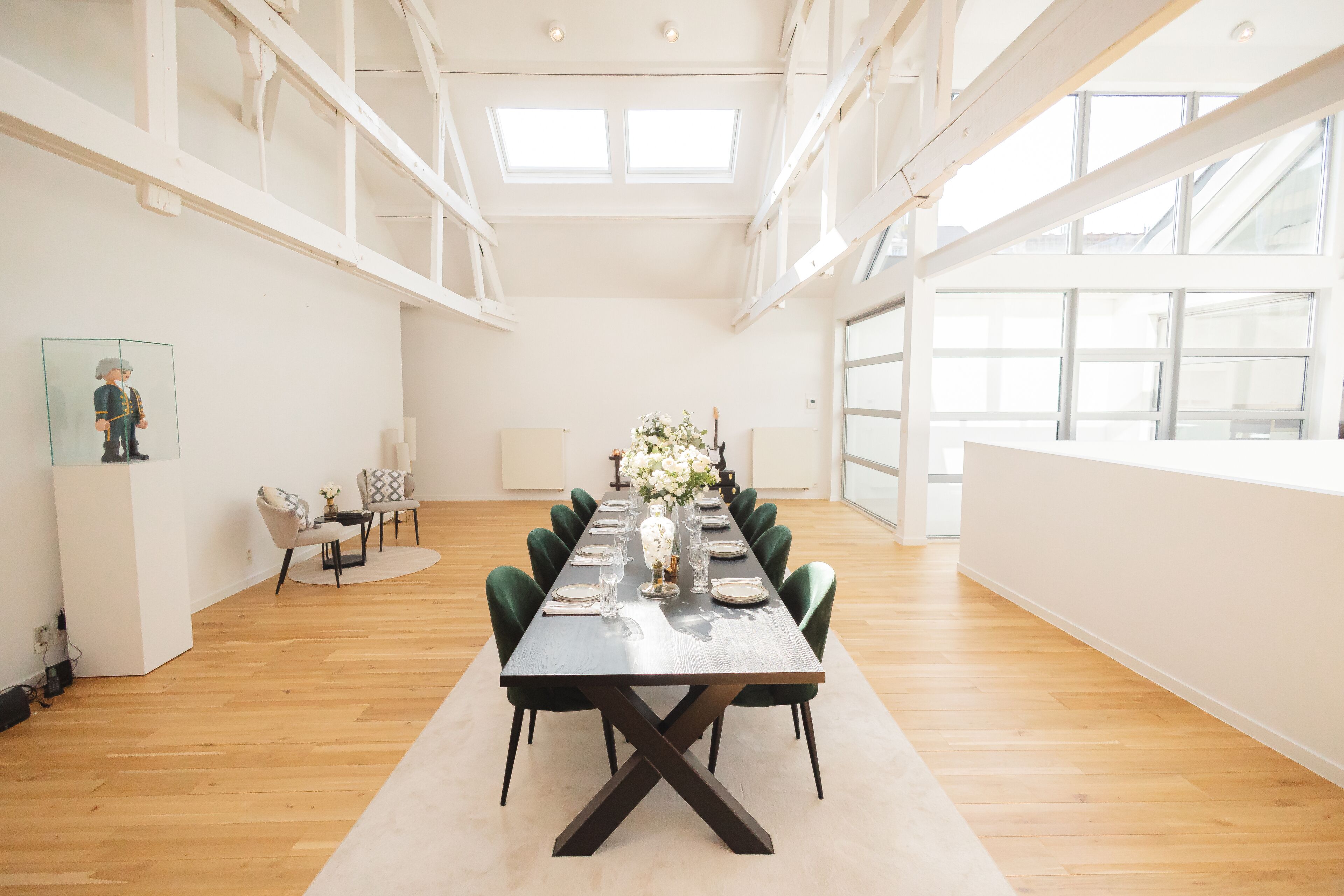 Une pièce spacieuse avec une longue table à manger dressée pour six personnes, entourée de chaises vertes.