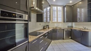 A modern kitchen with stainless steel appliances, a built-in oven, and a large window providing natural light.