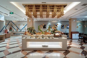 A modern hotel lobby with a central buffet area, check-in counters, and a patterned floor. - Grand Madison Hotel Linfen (Linfen)