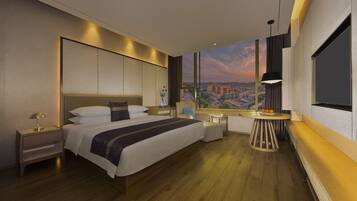 Ein modernes Hotelzimmer mit einem großen Bett, Nachttischen, einer kleinen Sitzecke und Blick auf die Stadt durch das Fenster.