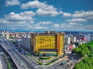 A multi-story hotel with a prominent yellow facade, surrounded by a busy urban environment with roads and other buildings. - Grand Madison Hotel Linfen (Linfen)