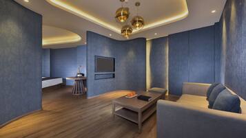 A modern interior with a curved ceiling, recessed lighting, a sofa, a coffee table, and a small round table with a book and oranges.