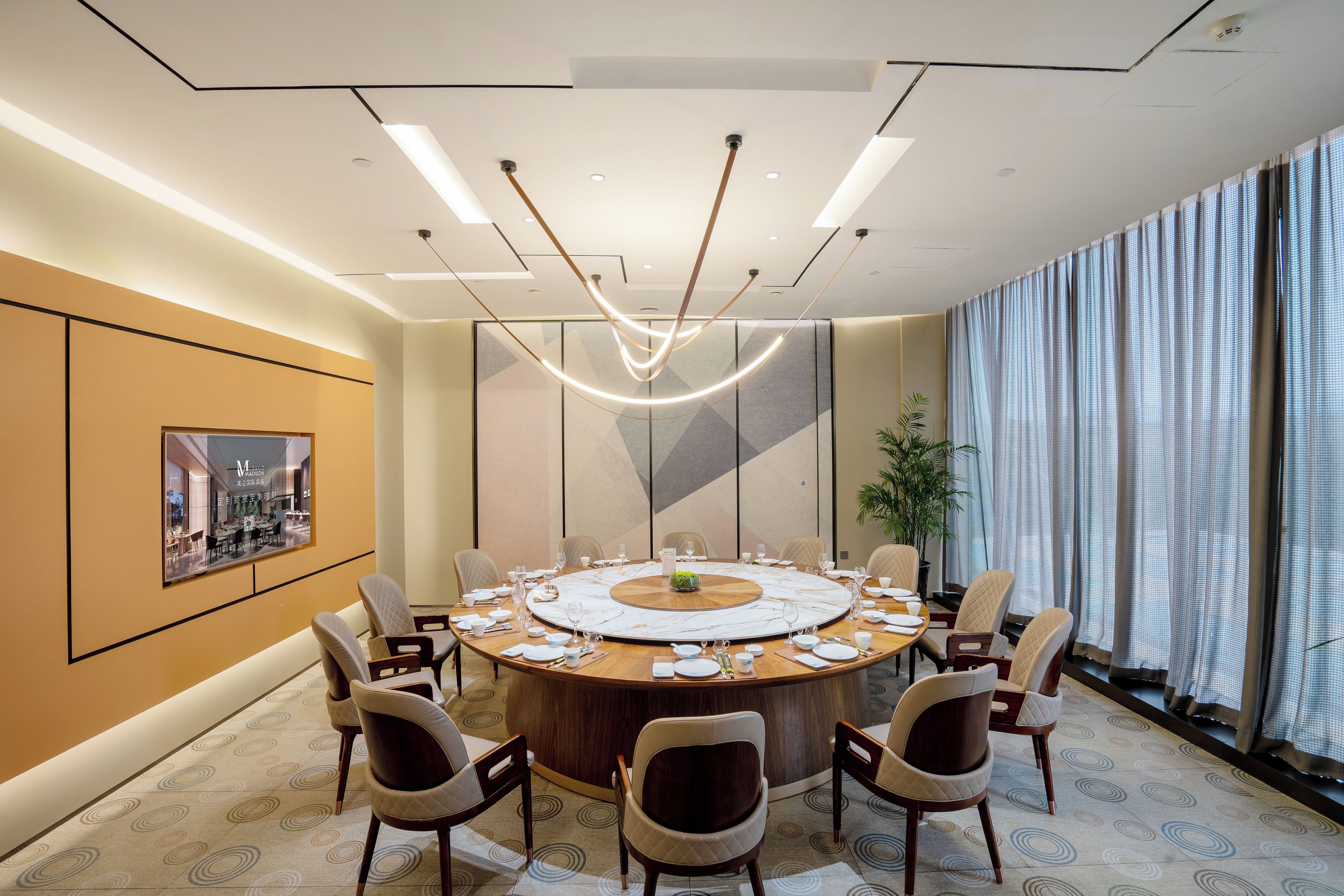 A conference room with a round table, chairs, and a large window with curtains.