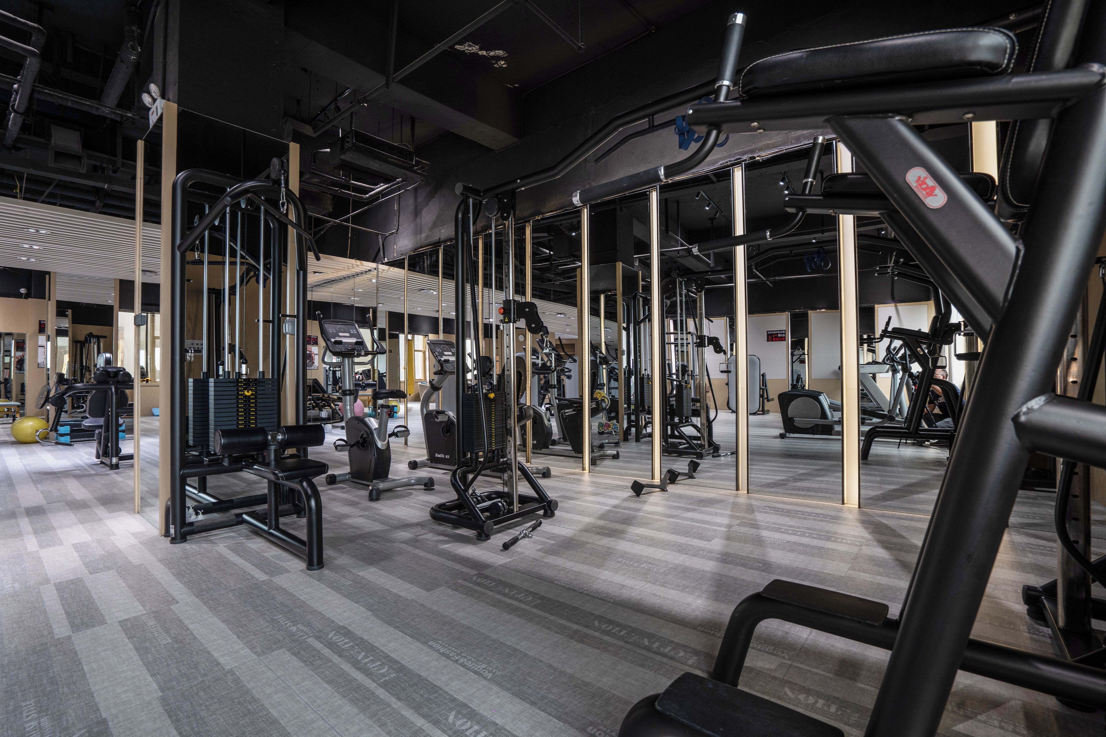Un gimnasio con varios equipos de ejercicio, incluyendo cintas de correr, máquinas de pesas y pesas libres.