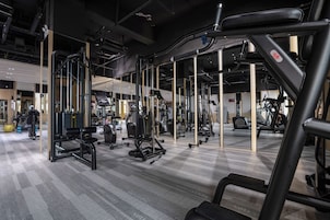 Un gimnasio con varios equipos de ejercicio, incluyendo cintas de correr, máquinas de pesas y pesas libres.