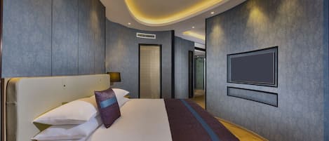 Une chambre d’hôtel moderne dotée d’un grand lit, d’un téléviseur à écran plat fixé au mur et d’un plafond au design incurvé.