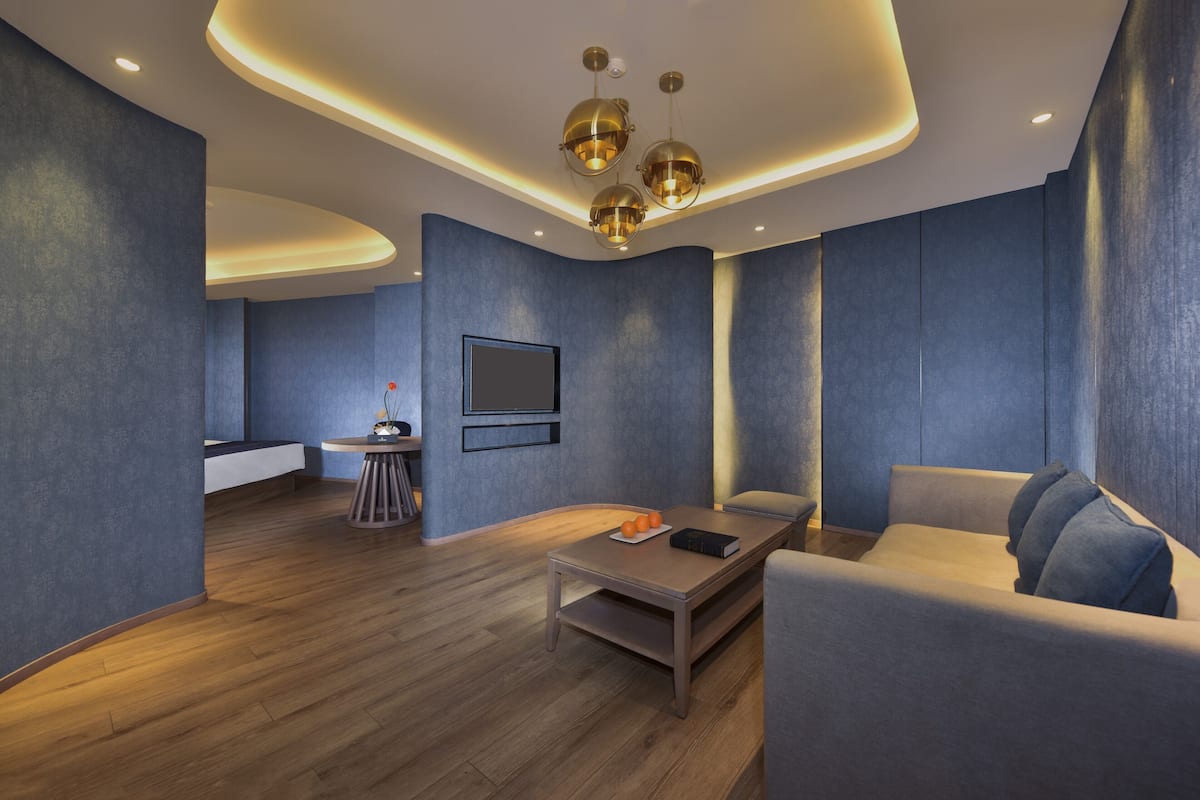 A modern interior with a curved ceiling, recessed lighting, a sofa, a coffee table, and a small round table with a book and oranges.