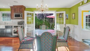 A modern kitchen with wooden cabinets, stainless steel appliances, and a large dining table with patterned chairs.