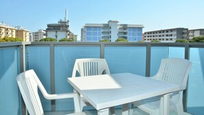 Eine Dachterrasse mit weißem Tisch und Stühlen, mit Blick auf die umliegenden Gebäude.