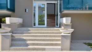 Ein moderner Gebäudeeingang mit einer Betontreppe, die zu einer Glastür führt.