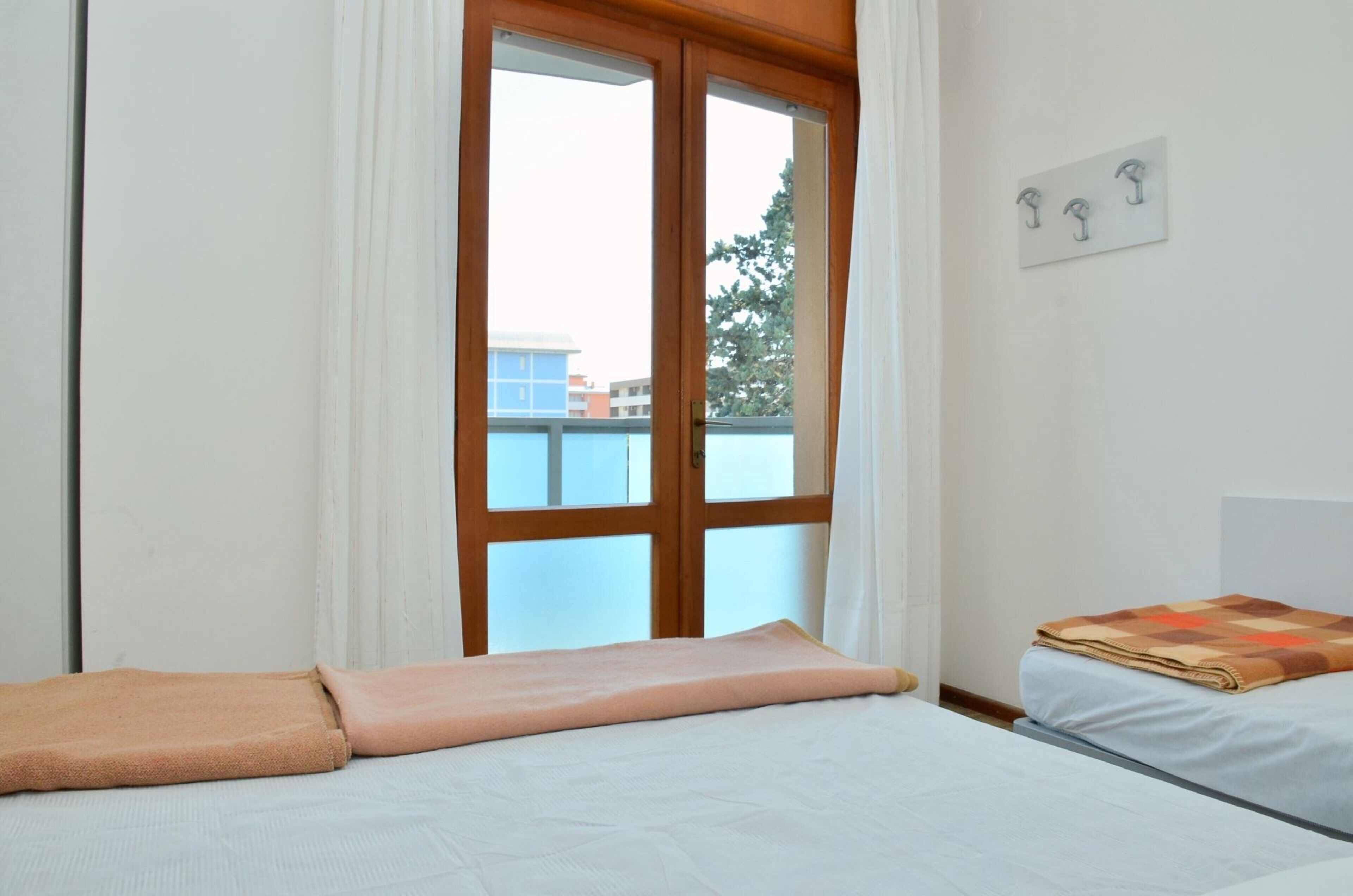 A bedroom with a bed, a window with curtains, and a wall-mounted hookboard.