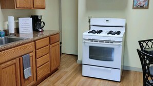 Une cuisine de taille réduite, avec des meubles de rangement en bois, une cuisinière blanche et une machine à café.