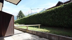 Un chemin pavé mène à un banc, une clôture en bois et une haie bien entretenue.