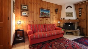 Un salon chaleureux avec un canapé rouge, des murs en bois, une cheminée et un tapis.