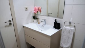 Een badkamer met een wit wastafelmeubel, spiegel en handdoekhouder.