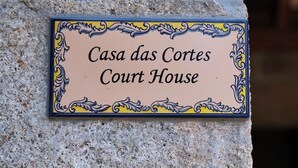 Een bord met de tekst 'Casa das Cortes Court House' op een stenen muur.