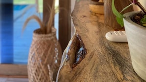Una mesa de madera con una planta en maceta, una cesta tejida y un control remoto.