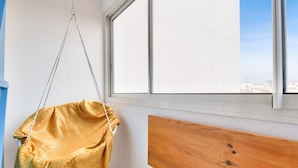 A room with a large window, a hanging chair, and a wooden bench. - 250m from the beach - Loggia - Flat for 4 (Saint-Hilaire-de-Riez)