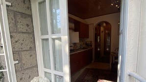 Una puerta que da a una habitación con cocina, techo de madera y felpudo.